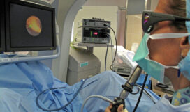 Dr. Dianne Sacco of Massachusetts General Hospital uses a laser ureteroscope to pulverize a kidney stone in Henry Owens. The screen shows a magnified image of the stone, an irregular yellow shape.